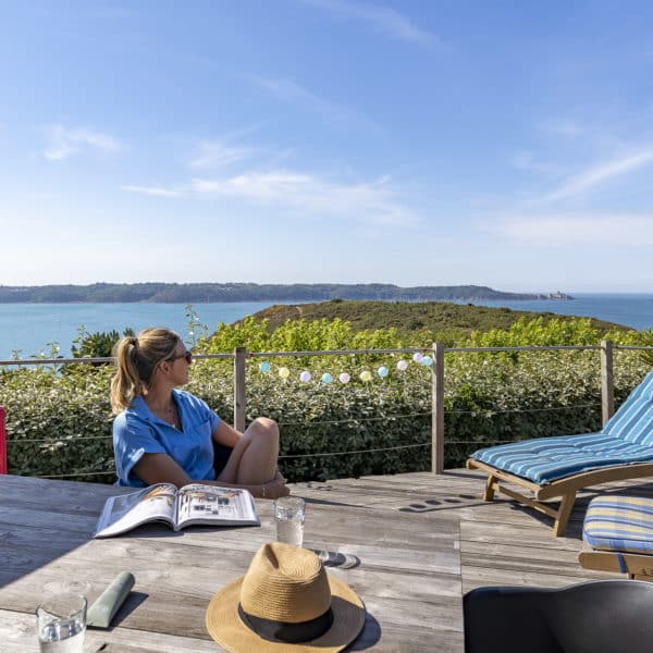 Terrasse avec vue sur mer et femme heureuse.