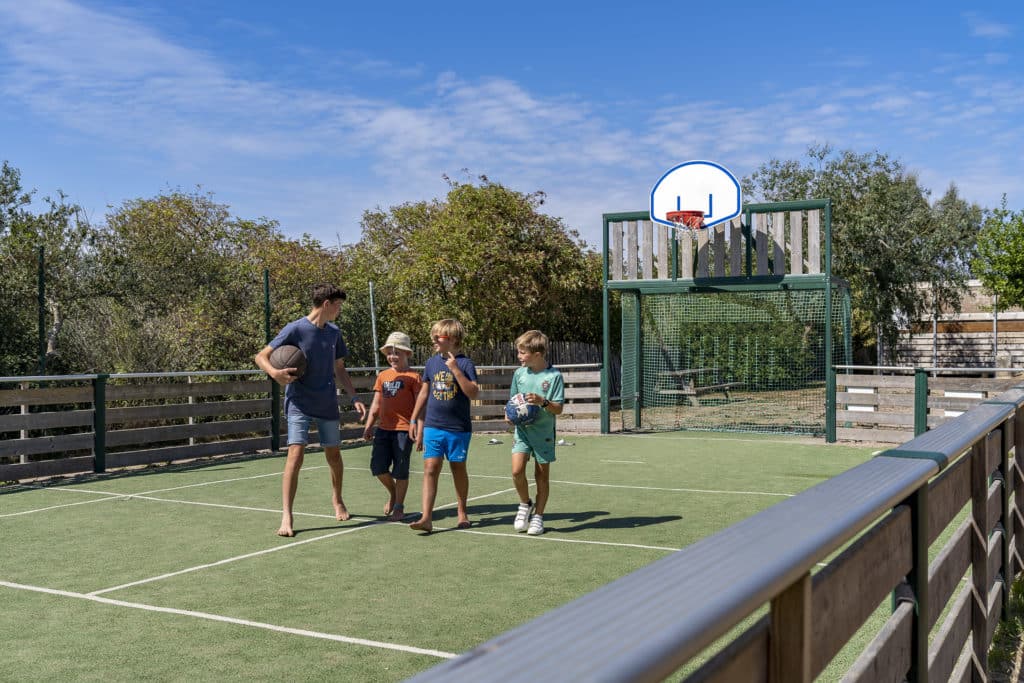 Enfants jouant au basket sur terrain extérieur.
