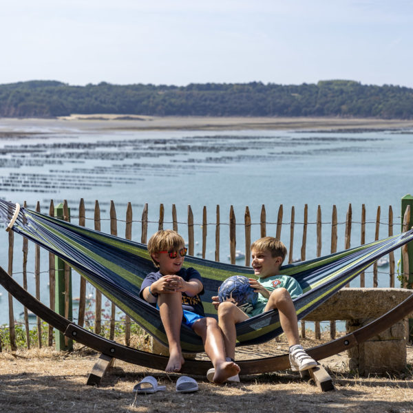 Twee kinderen in een hangmat met uitzicht op de oceaan