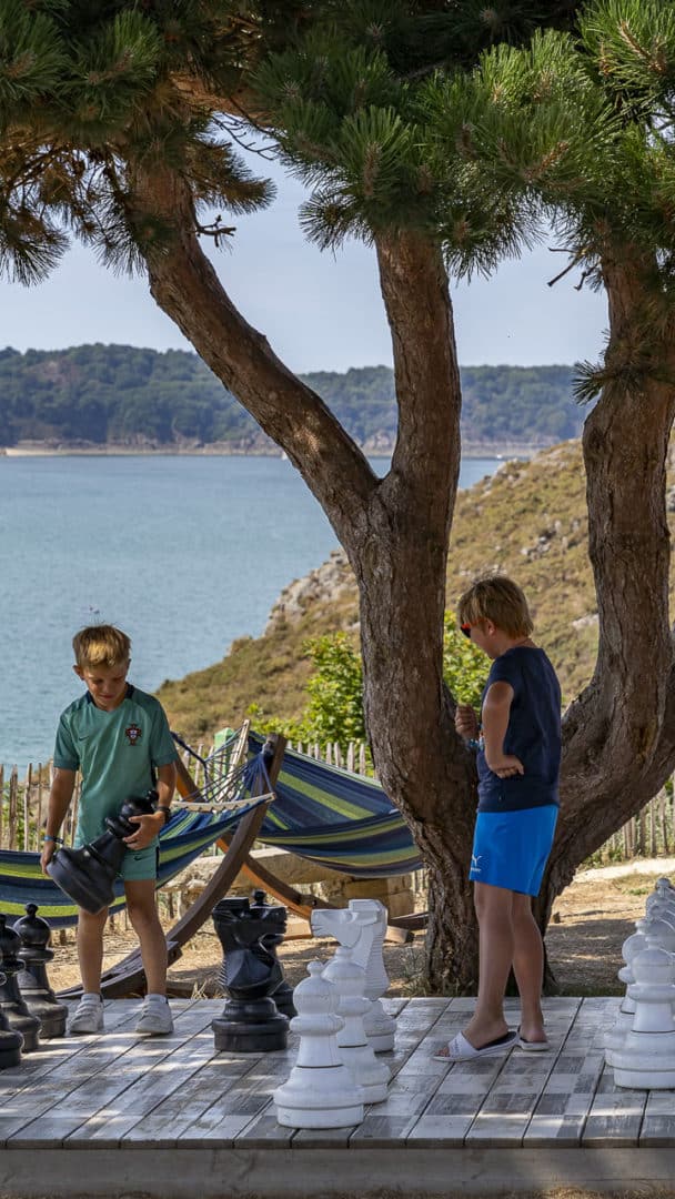 Enfants jouent aux échecs géants près de la mer.