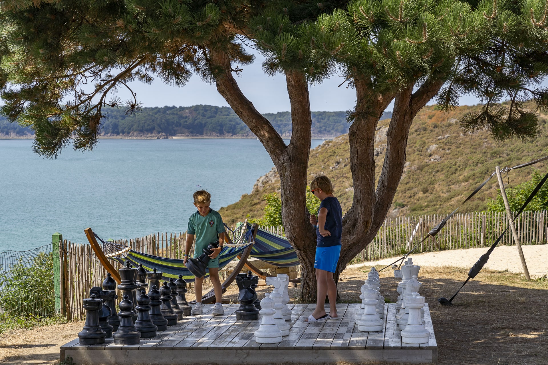 Enfants jouent aux échecs géants près de la mer.