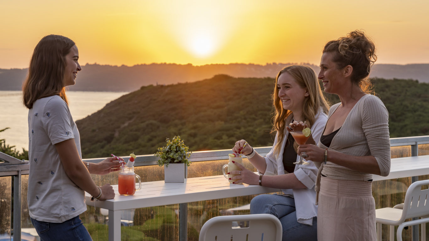 Trois femmes qui échangent autour d'un verre au coucher du soleil