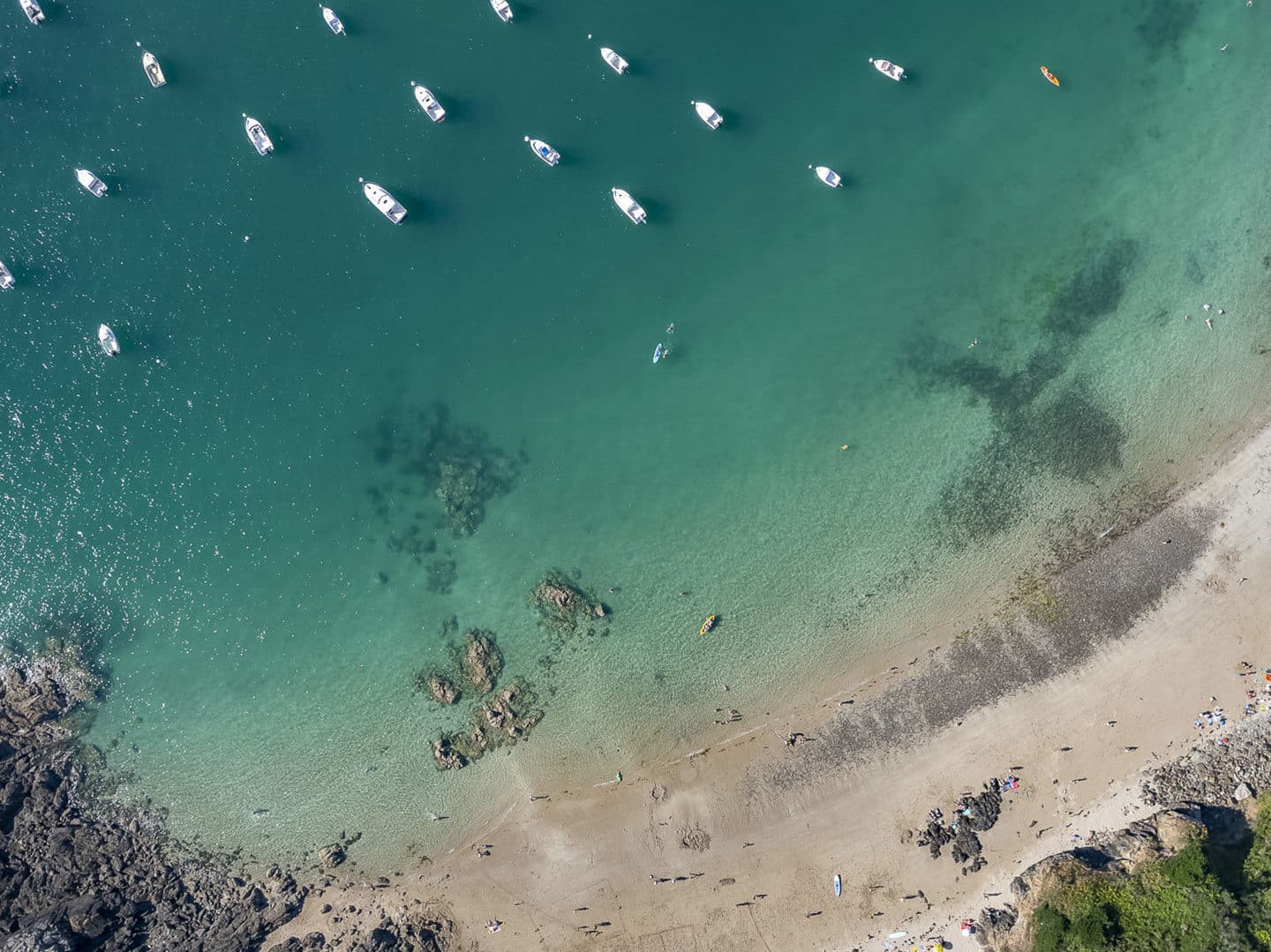Vue aérienne plage et bateaux, eau turquoise, côtes rocheuses.